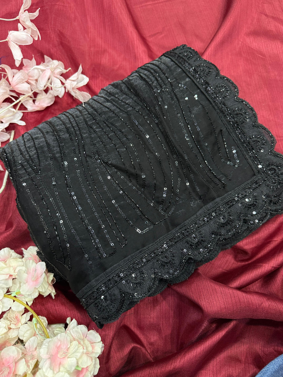 The saree in the image is crafted from sequin-embroidered net or organza fabric, layered over a smooth satin or silk-blend inner petticoat and blouse.