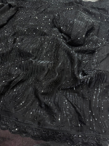 The saree in the image is crafted from sequin-embroidered net or organza fabric, layered over a smooth satin or silk-blend inner petticoat and blouse.